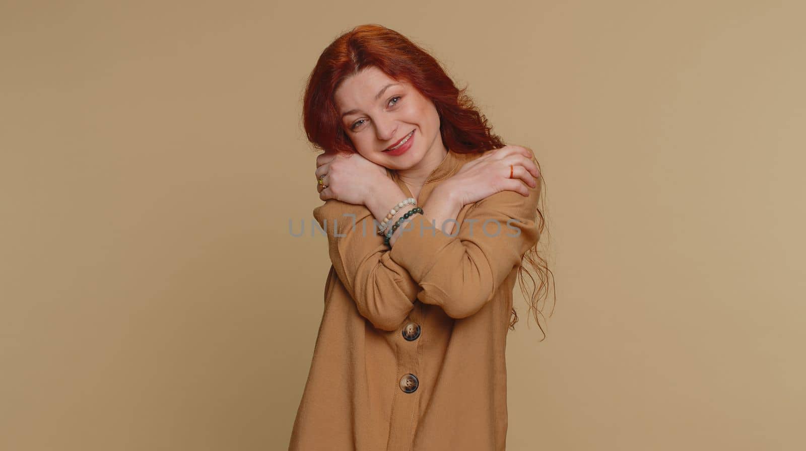 Come to me, I want to embrace you. Happy smiling redhead woman spread hands and give hug to you. Pleasant expression, love feelings. Young ginger girl isolated alone on beige studio background