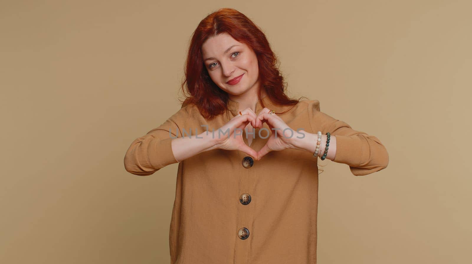 Smiling pretty woman makes heart gesture demonstrates love sign expresses good feelings and sympathy by efuror