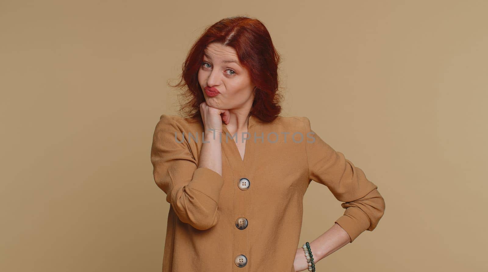 Sad redhead woman tired bored indifferent expression, exhausted of tedious story, not interested in communication talk, displeasure, uninteresting. Young girl isolated alone on beige studio background