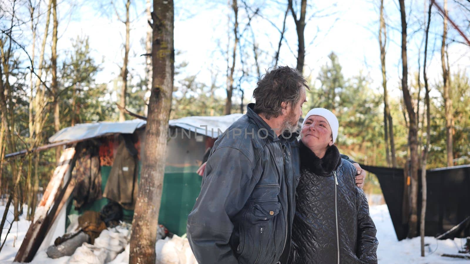 A homeless woman and a man pose in the woods in winter
