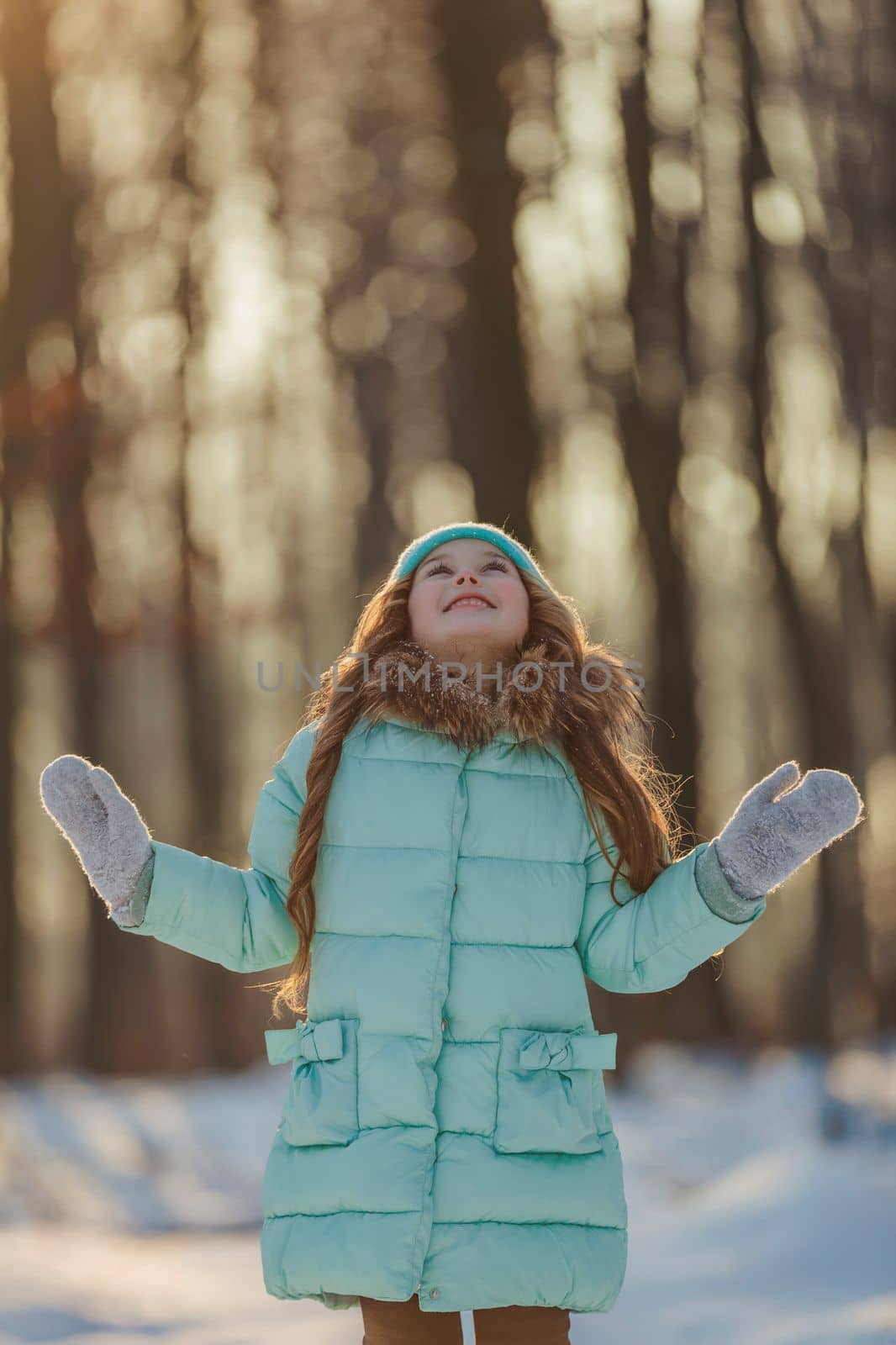 girl in a turquoise squat and a hat in the winter forest by zokov