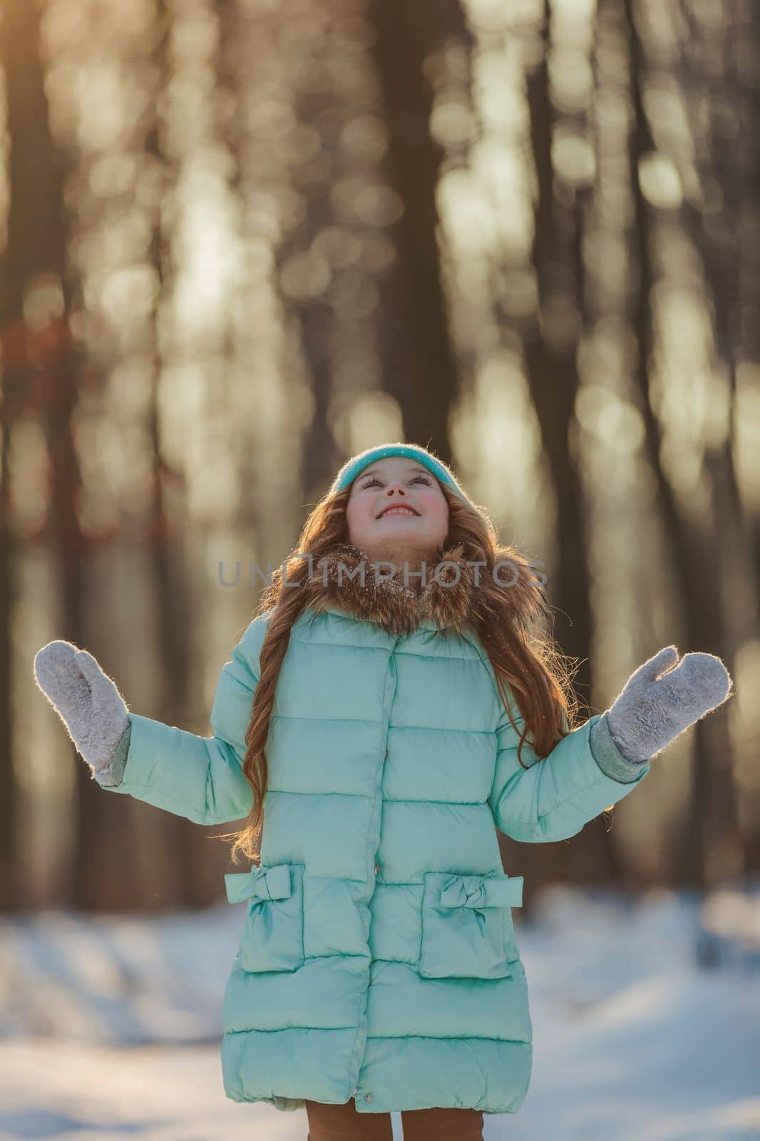 girl in a turquoise squat and a hat in a winter forest, shot vertically