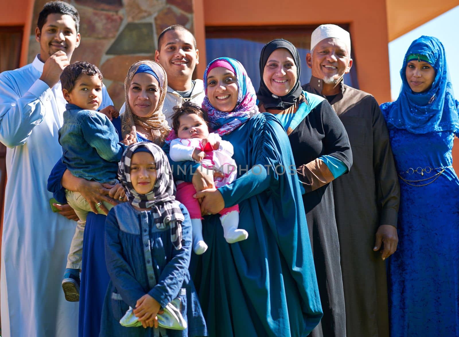 Proud of our family. Portrait of a happy muslim family standing together in front of their house. by YuriArcurs