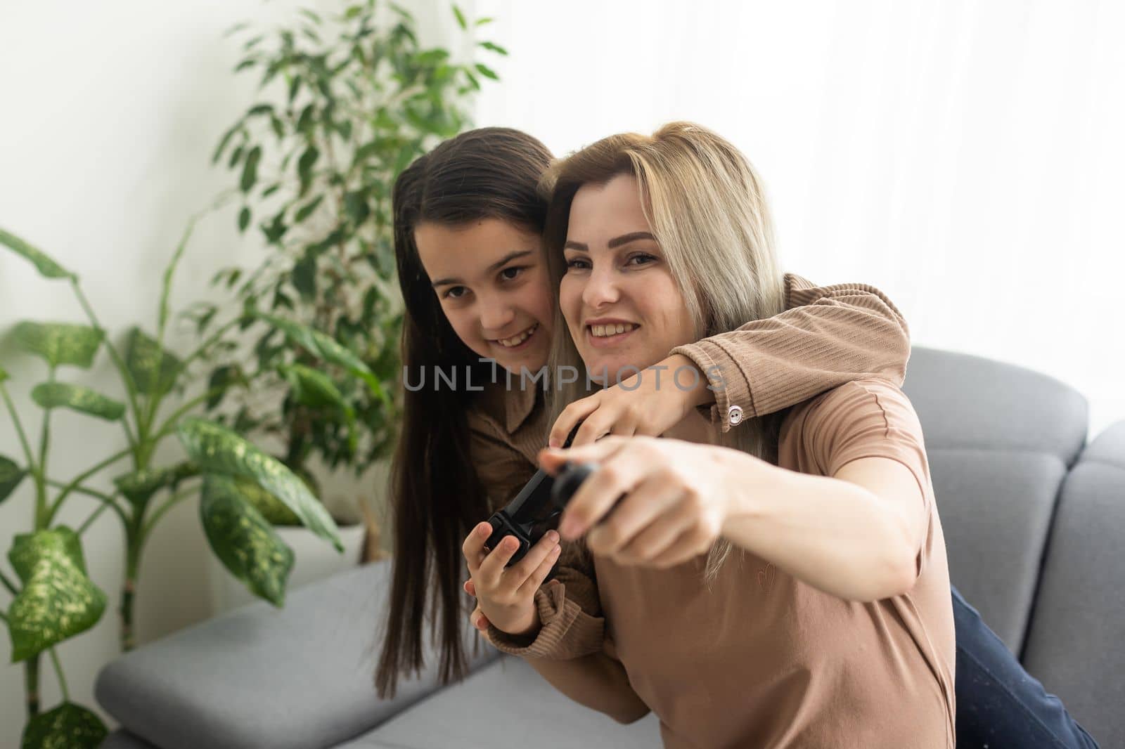 Happy family together. Mother and her child girl playing video games. People having fun at home.