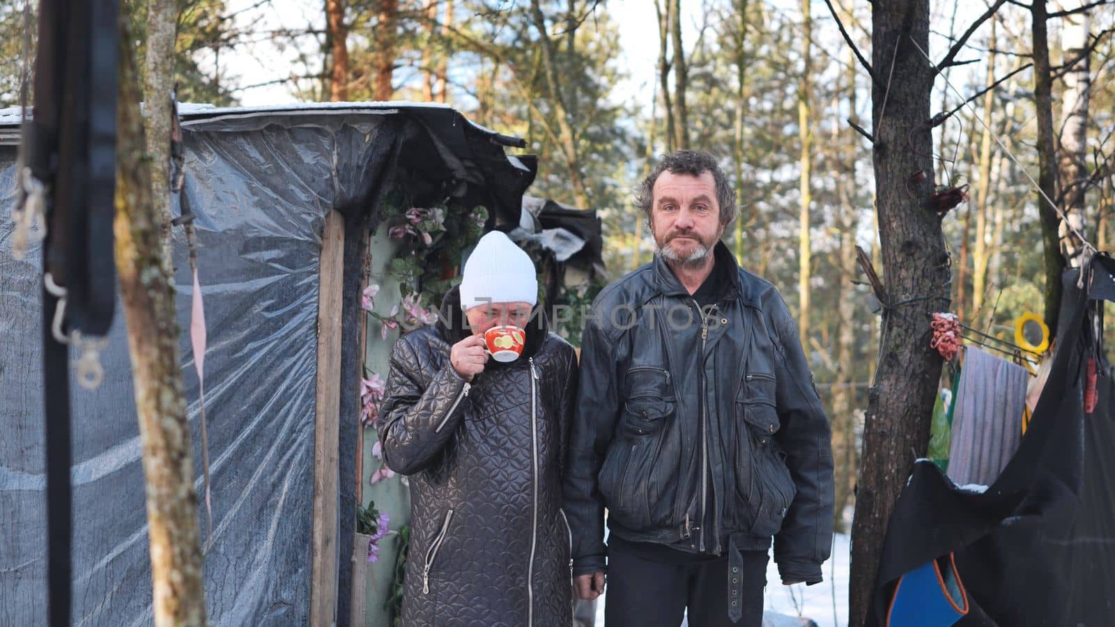 A homeless man and woman giving an interview in the winter in the woods