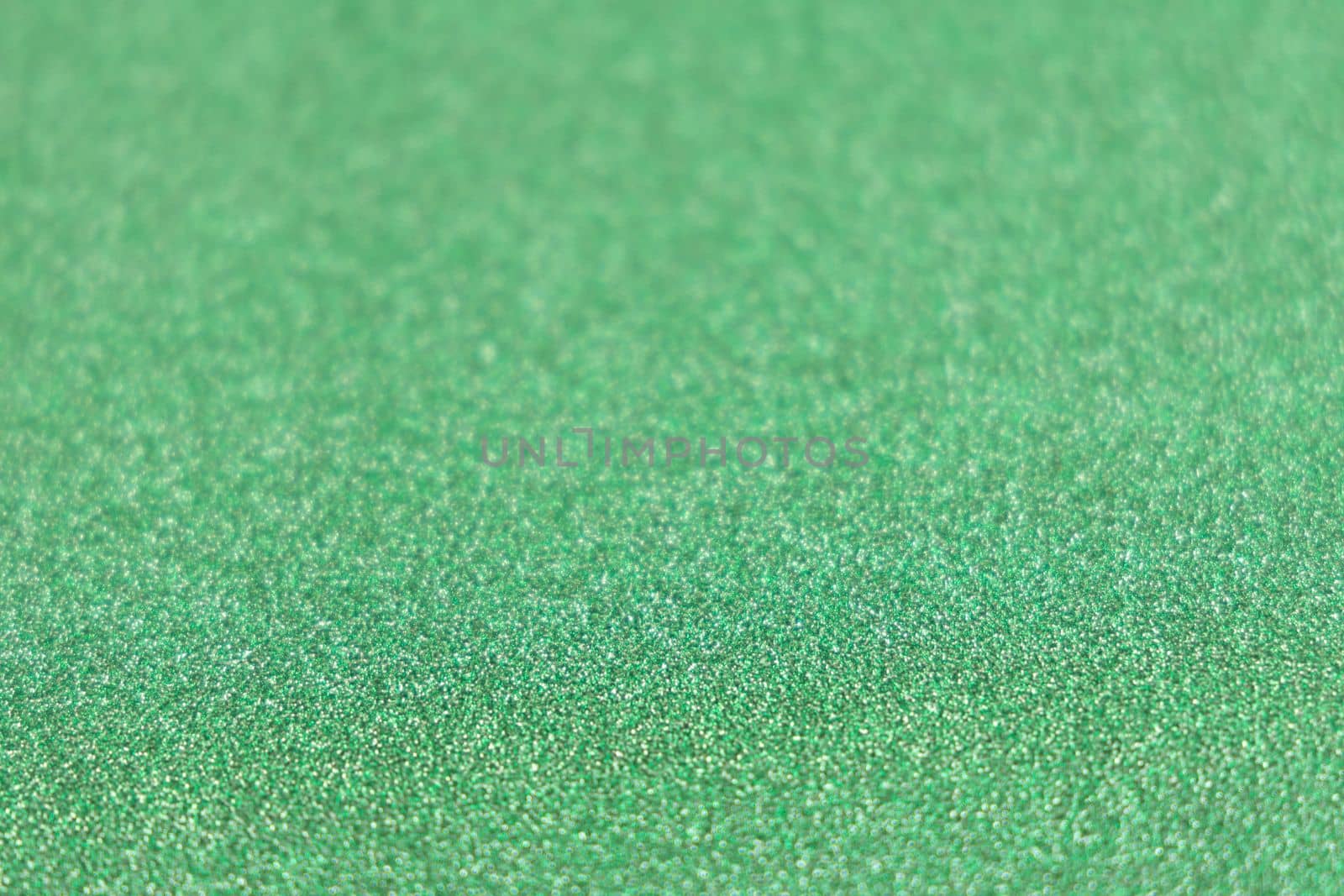Green shiny glitter paper texture. Shining luxurious fabric. Glimmering golden christmas background paper texture. Shining luxurious fabric. Glimmering light green color st Patric, christmas background.