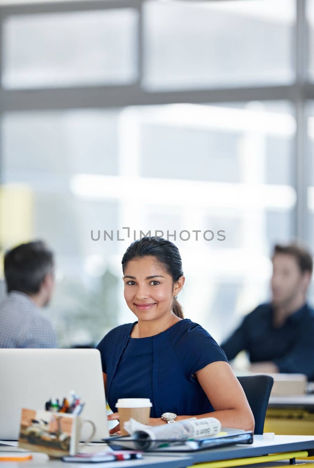 My career path is going exactly as I planned. Portrait of a designer sitting at her desk working on a laptop with colleagues in the background