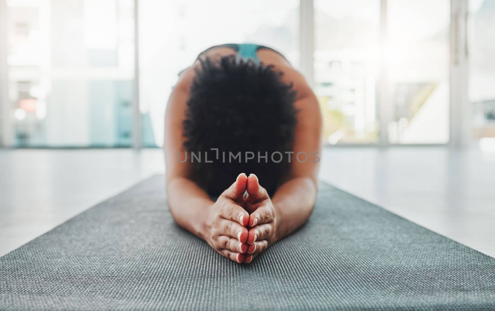 Yoga, arm stretching and prayer hands of a black woman in a gym for zen, relax and exercise. Pilates, peace and meditation training of an athlete in prayer pose on the floor feeling calm from stretch.