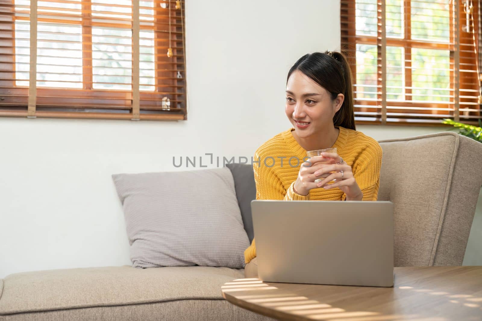 Happy Asian woman while using her laptop in the living room. work from home by nateemee