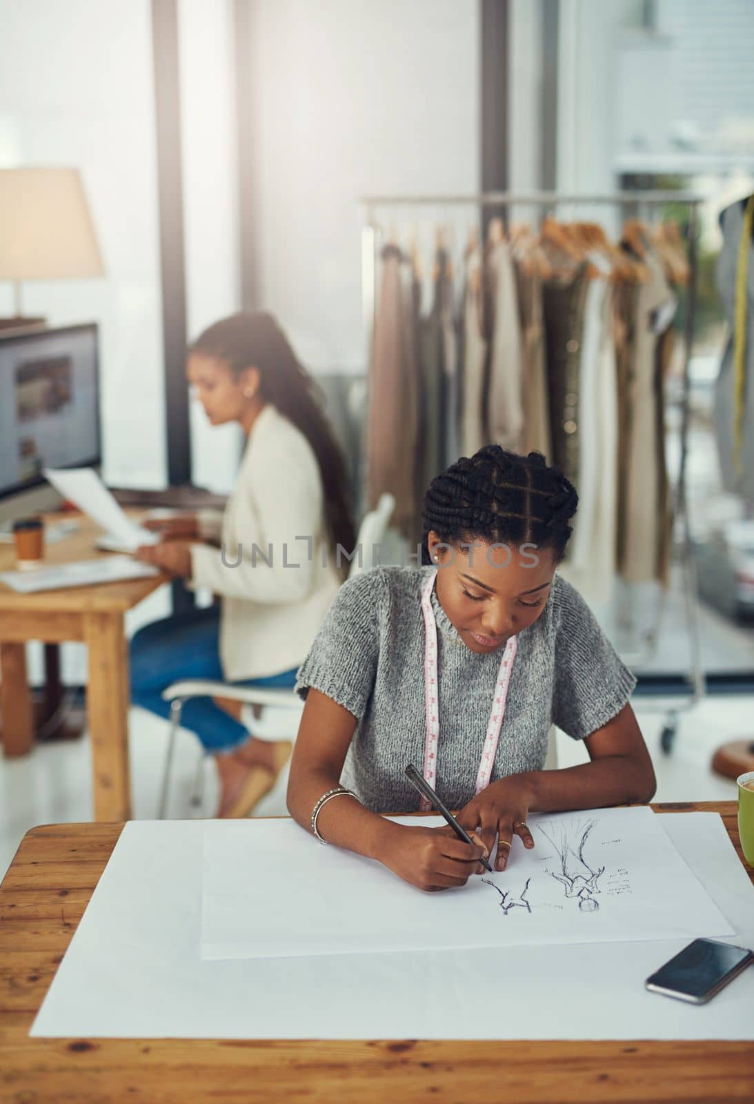 Changing the world one design at a time. a fashion designer working on her latest creation with her colleague blurred out