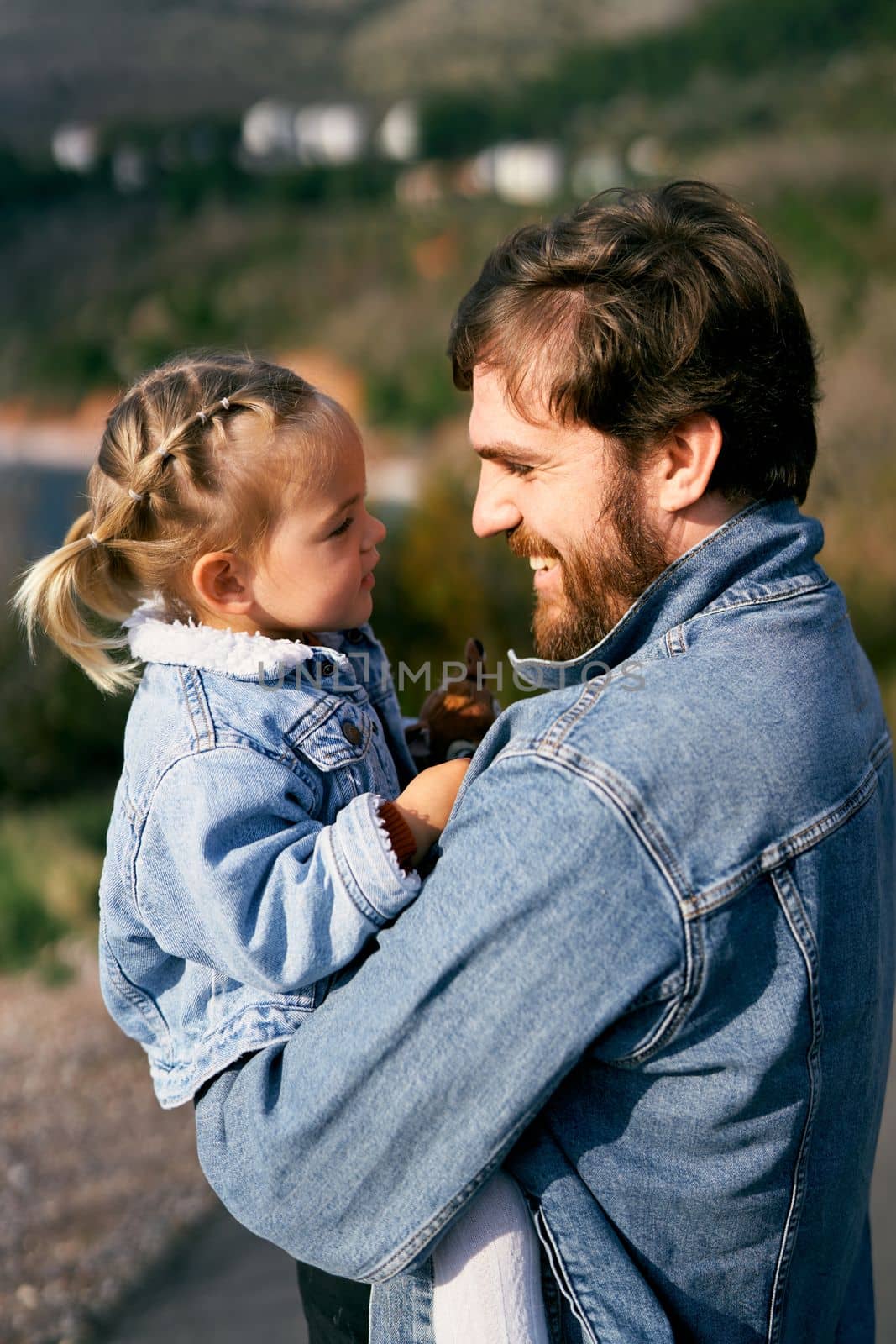 Smiling dad holds a smiling little girl face to face in his arms. Close-up. High quality photo