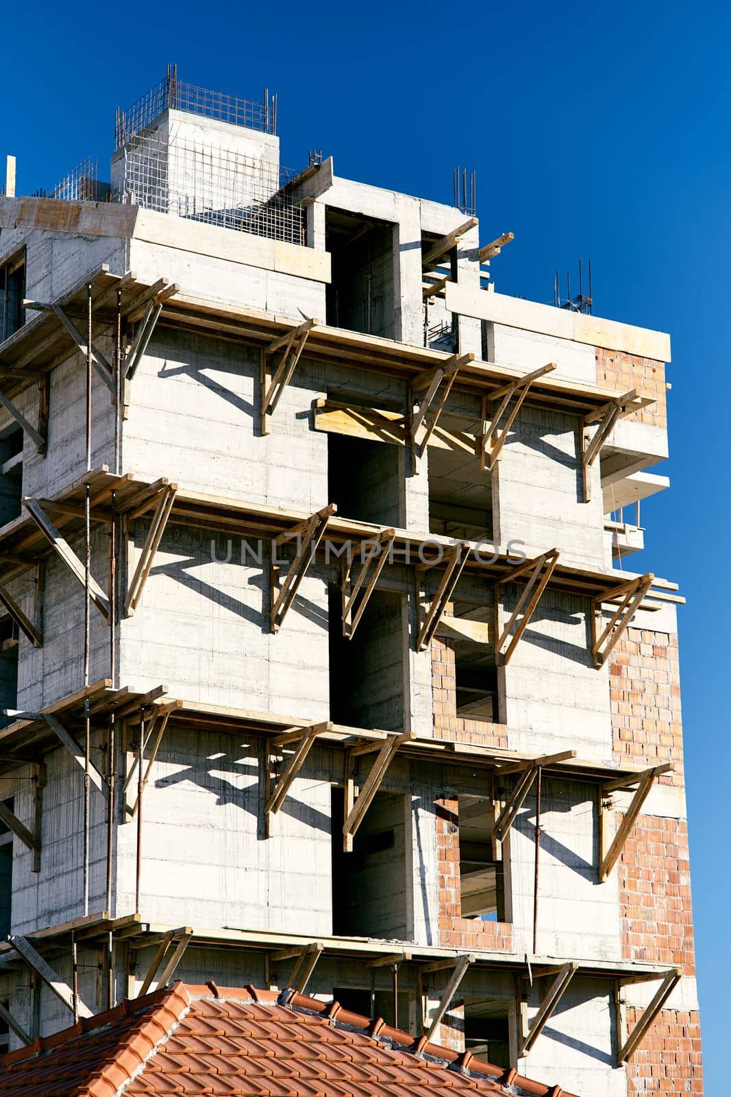 Scaffolding on the facade of an apartment building under construction against the background of a bright blue sky. Close-up. High quality photo