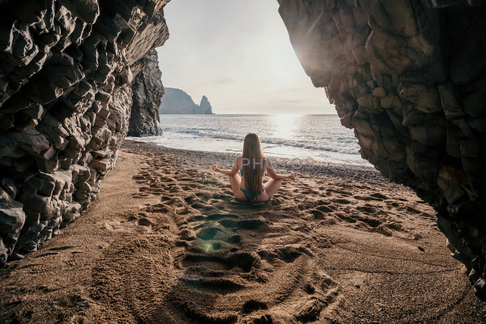 Middle aged well looking woman with black hair doing Pilates with the ring on the yoga mat near the sea on the pebble beach. Female fitness yoga concept. Healthy lifestyle, harmony and meditation.