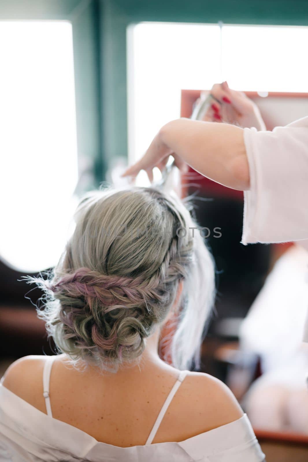 Hairdresser makes the bride an elaborate hairstyle. Close up. High quality photo