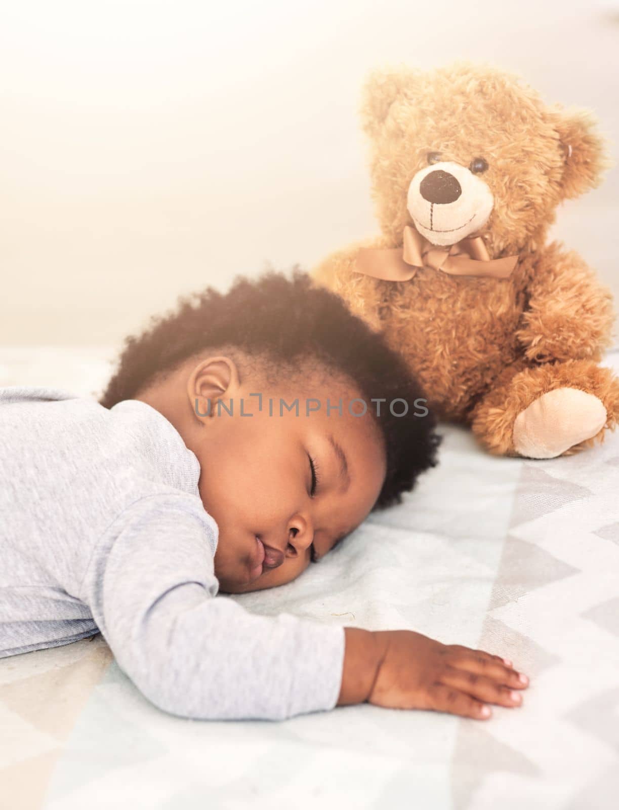 Teddy watches over him while he sleeps. a little baby boy sleeping on a bed
