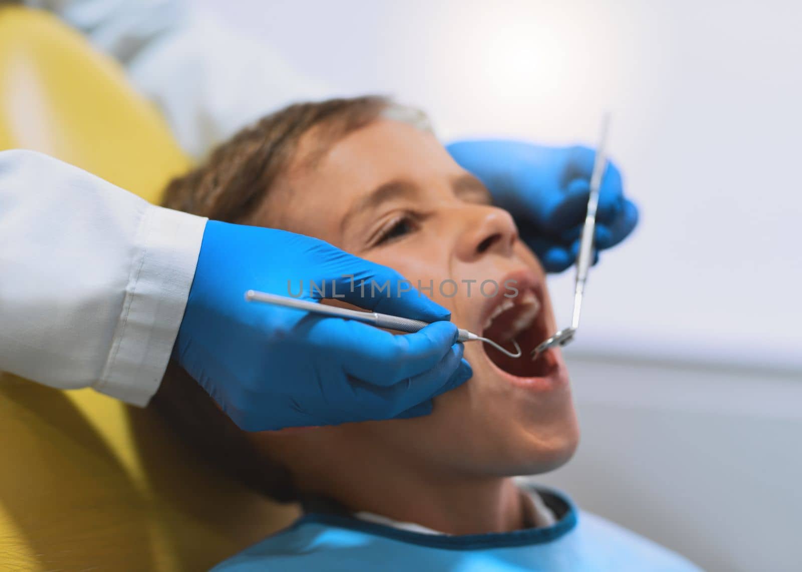 Everything looks in place. a young little boy lying down on a dentist chair while getting a checkup from the dentist