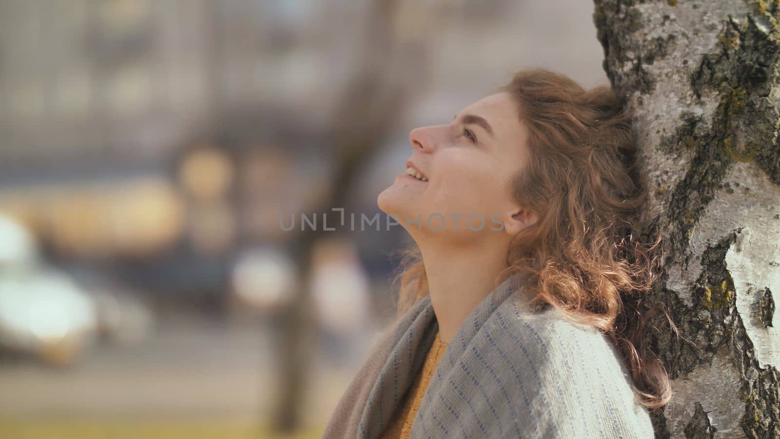 Portrait of a curly-haired redheaded girl outside by a tree