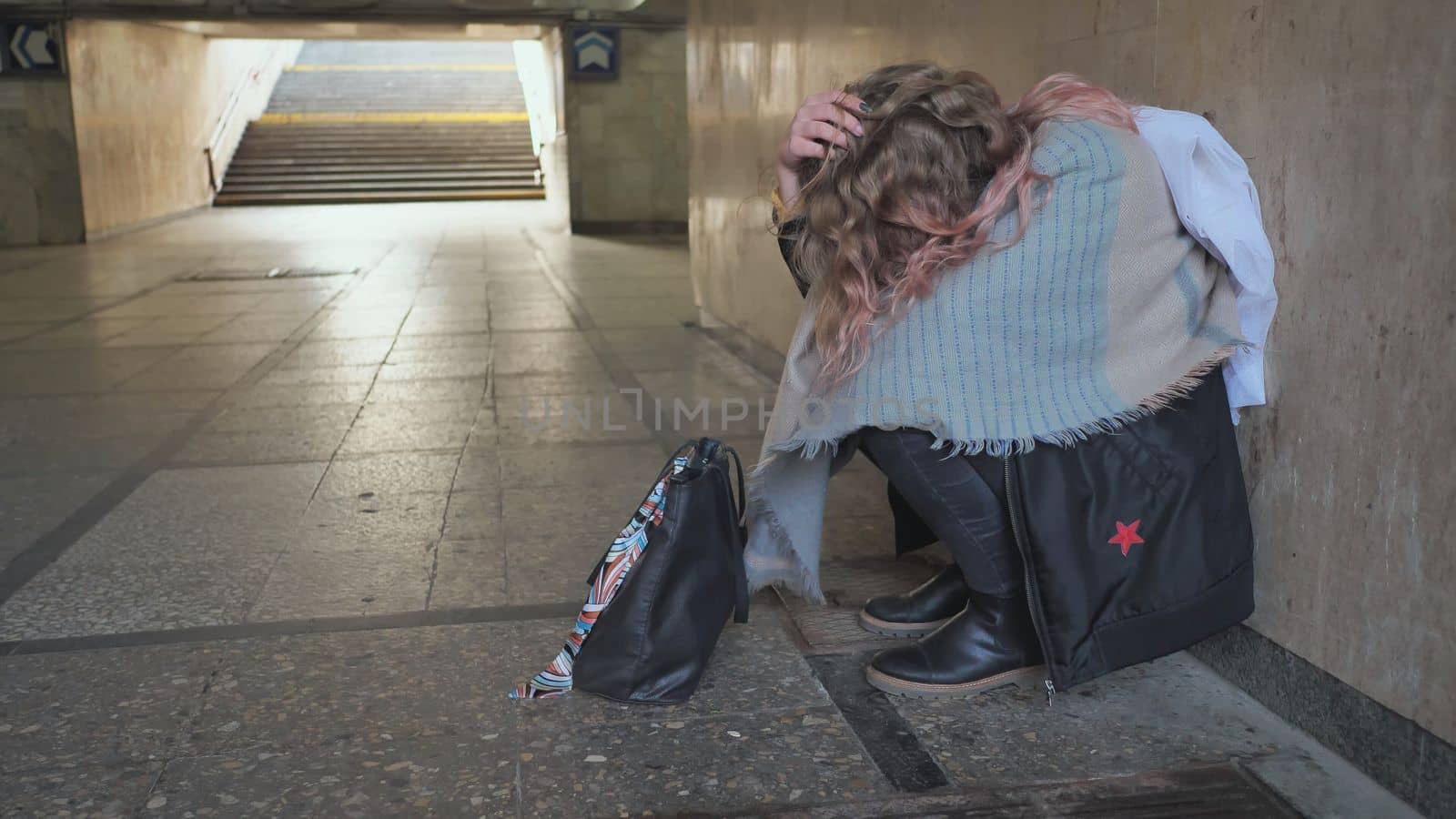 A lonely, sad girl sitting in an underpass