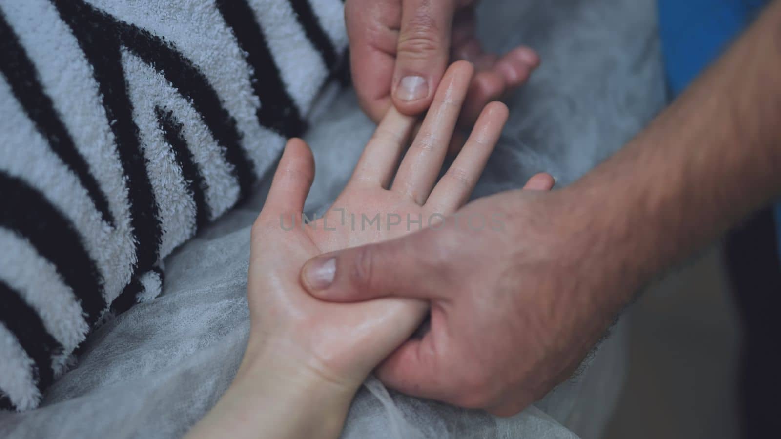 A masseur massages the wrists of a girl