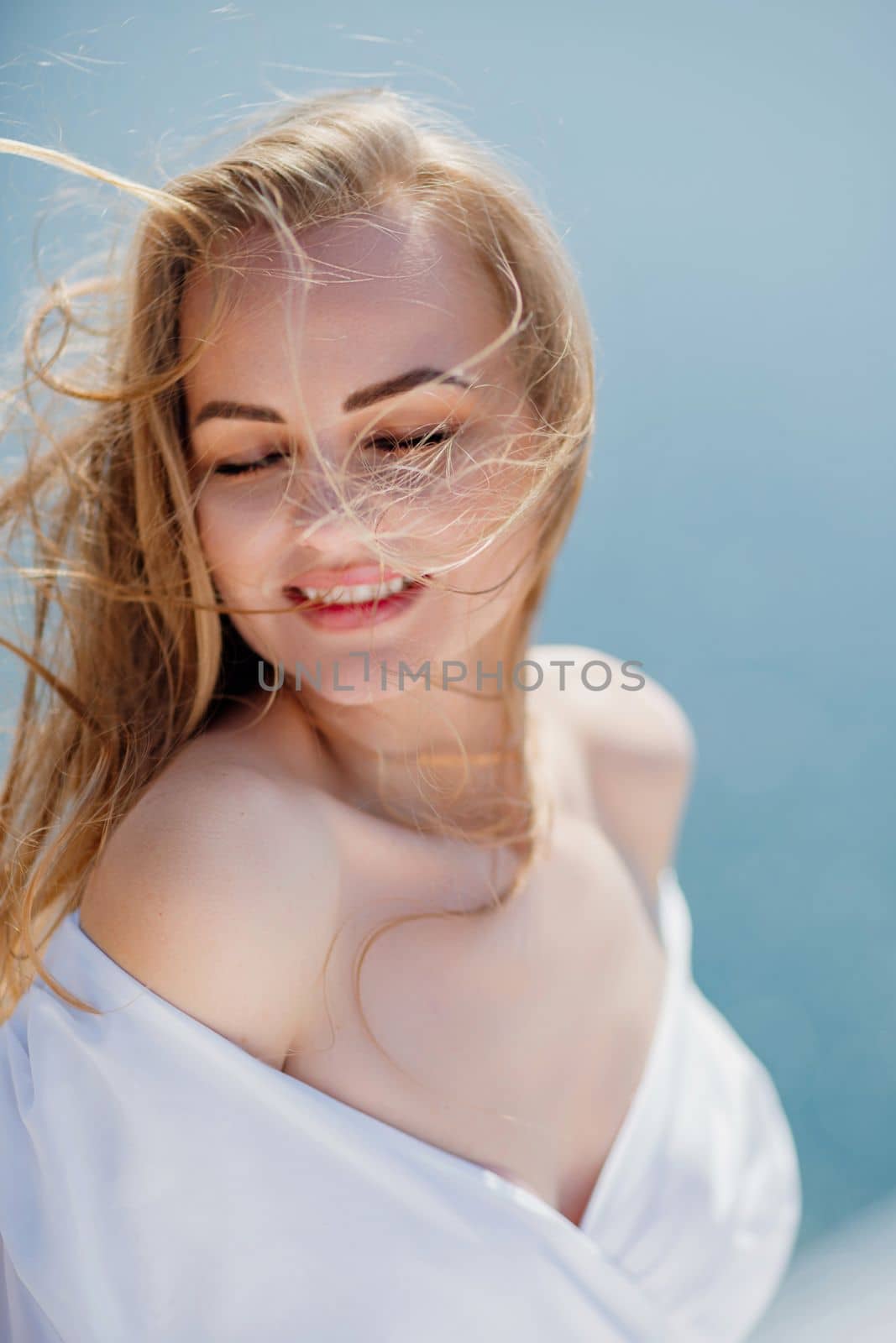 Portrait of a blond woman at the sea, a woman makes photos for memory from a trip to the sea to show to friends