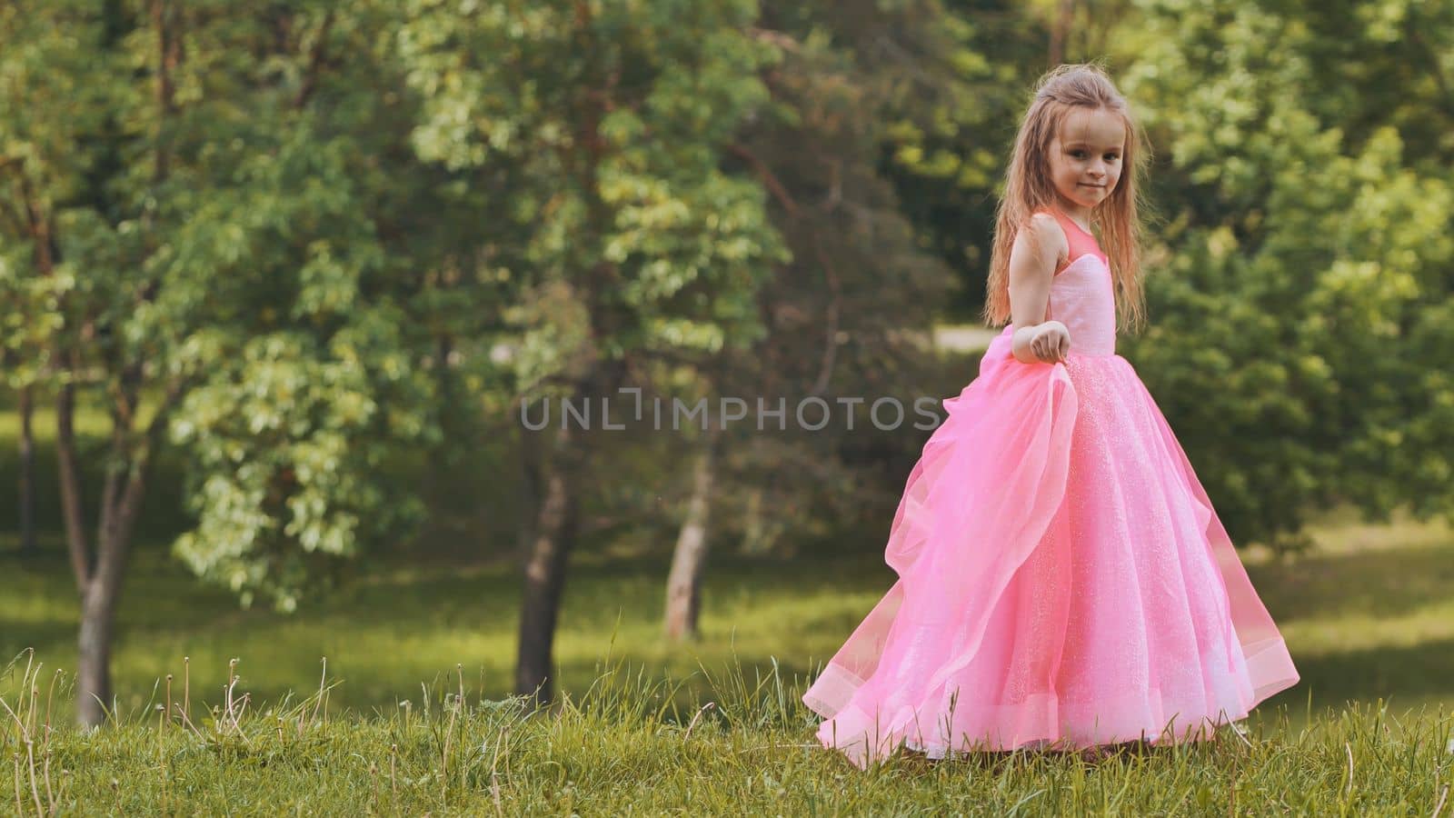 A girl in a pink princess dress is walk in the park