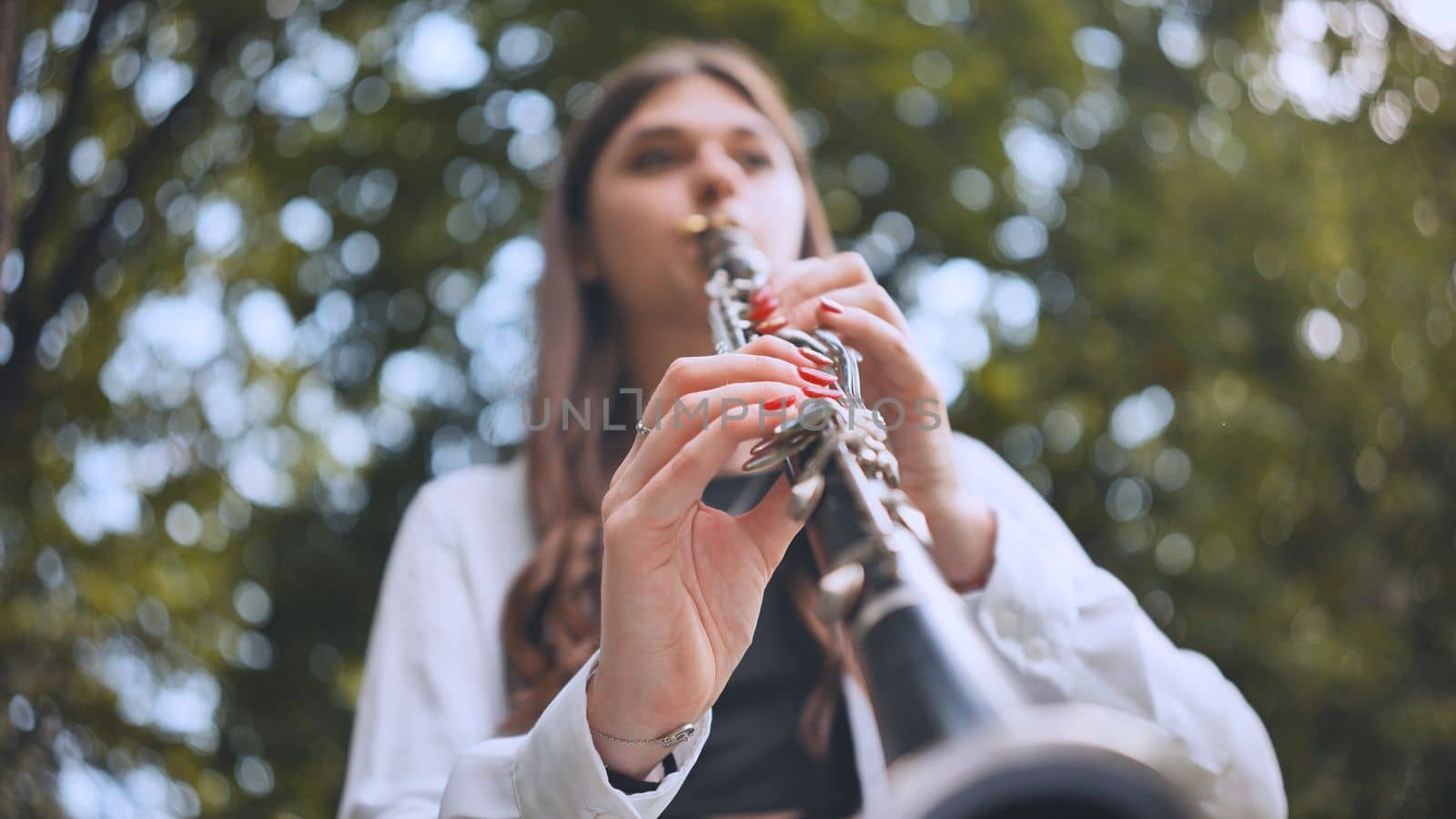 A girl plays the clarinet in the park in the summer