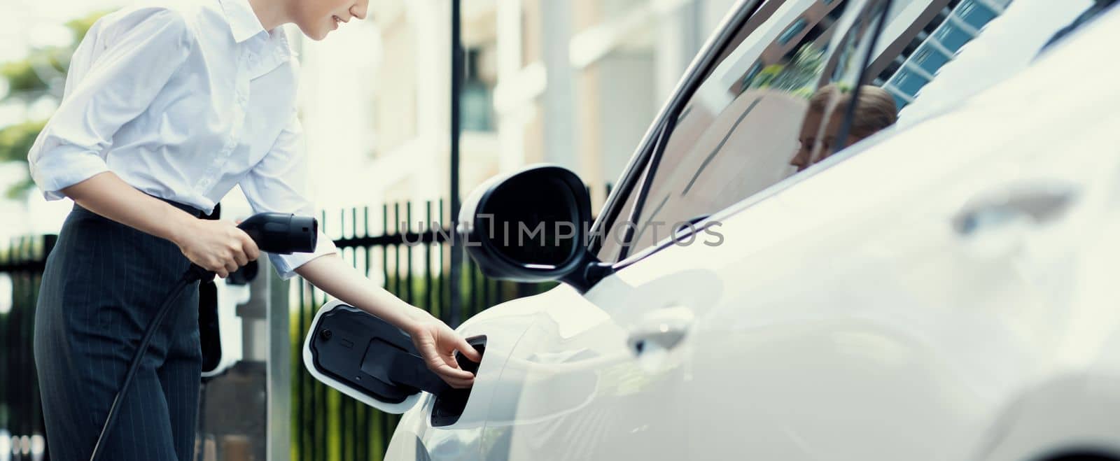 Closeup progressive woman talking on the phone, leaning on electric vehicle. by biancoblue