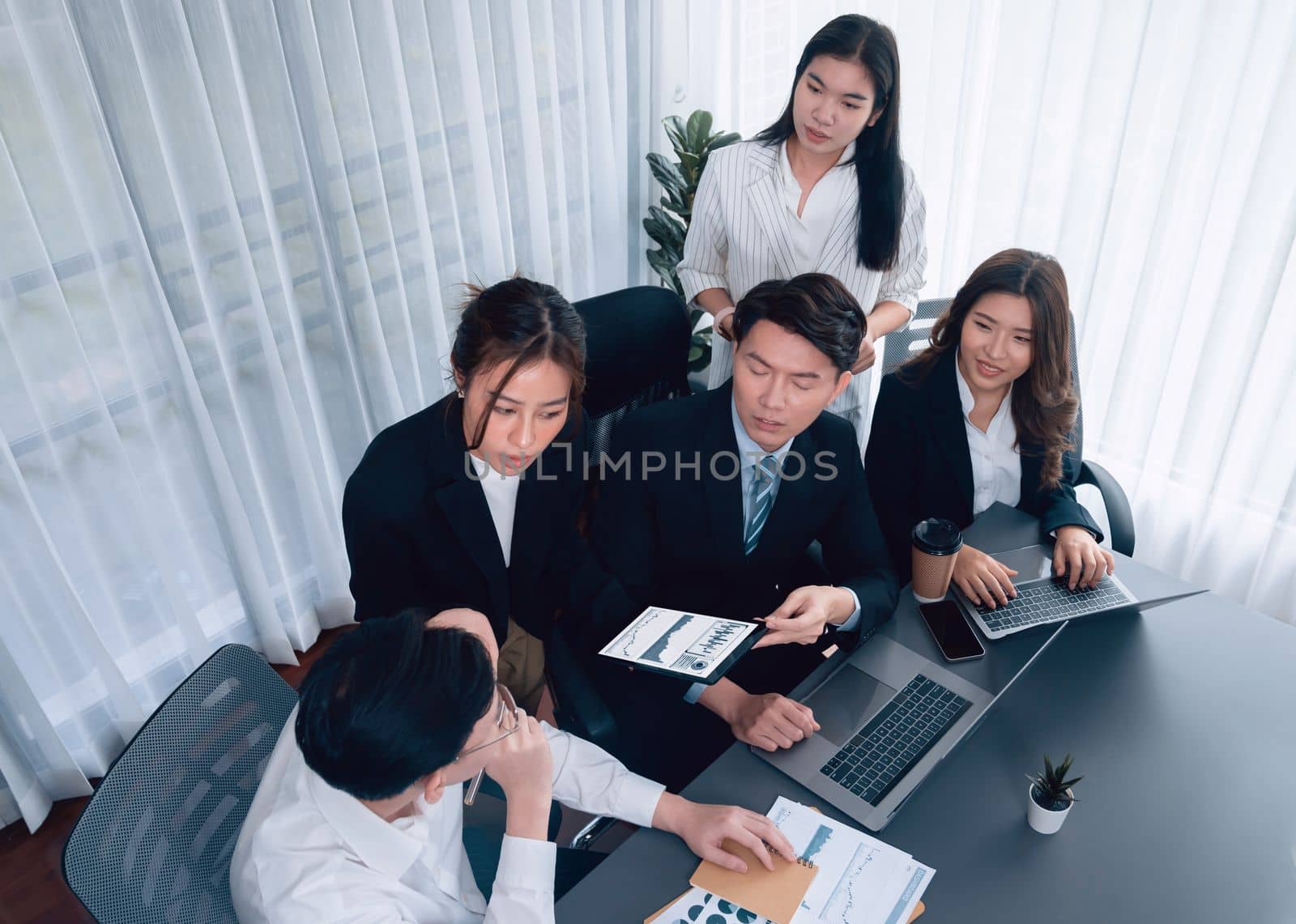 Harmony in office concept as business people analyzing dashboard paper together in workplace. Young colleagues give ideas at manager desk for discussion or strategy planning about project.