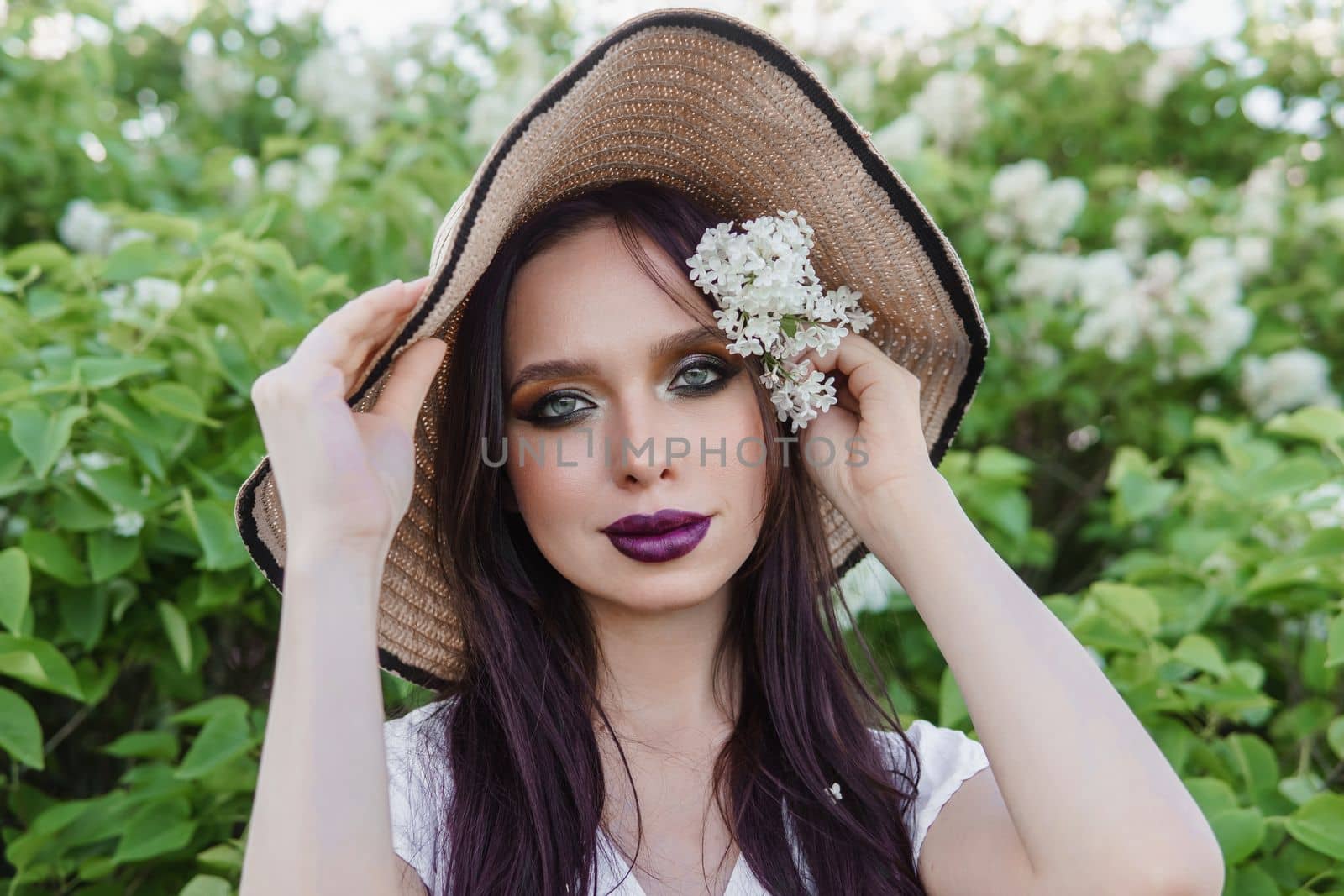 A fashionable girl with dark hair, a spring portrait in lilac tones in summer. Bright professional makeup