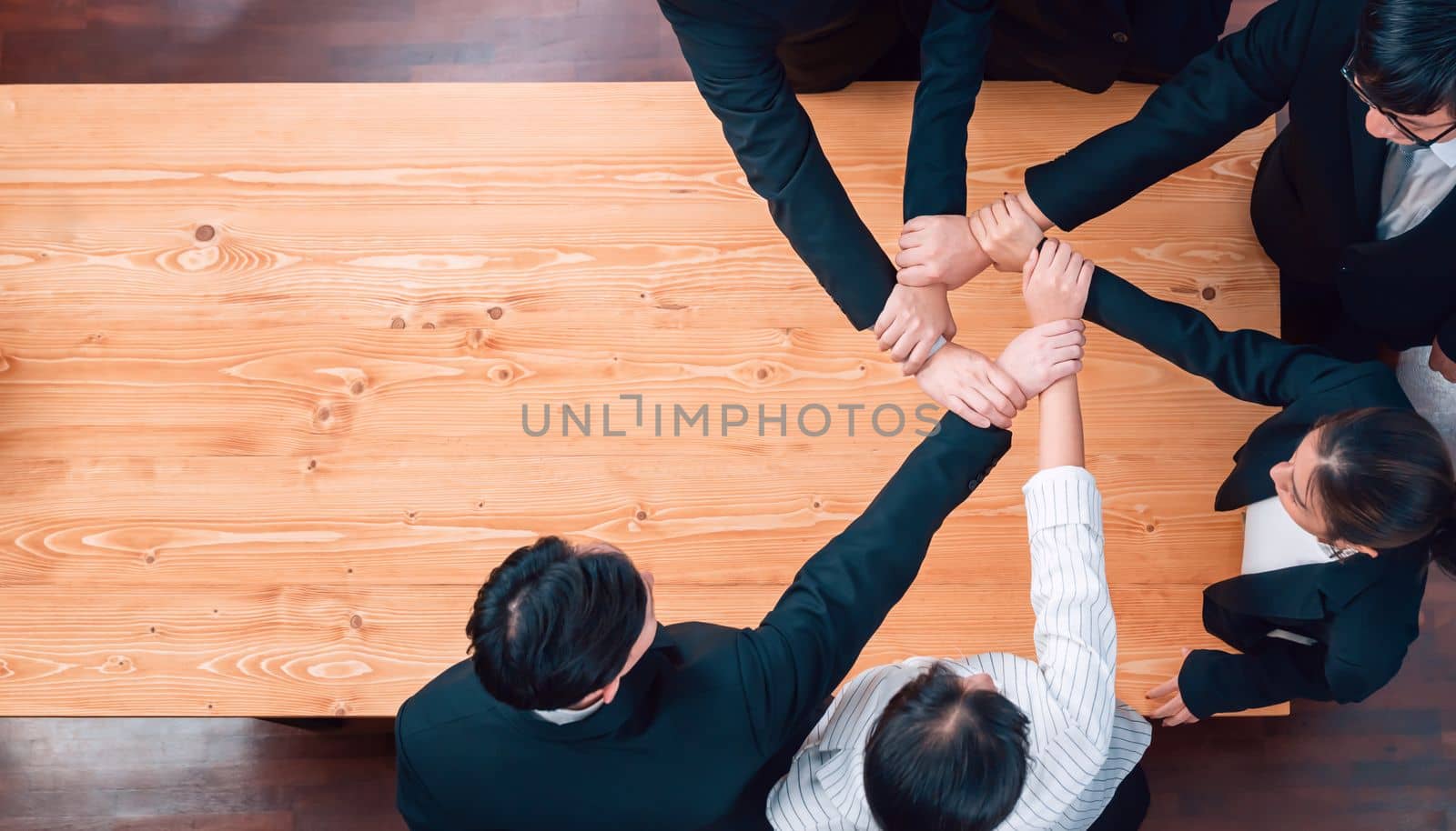 Top view cohesive group of business people join hands stack together, form circle over meeting table for copyspace. Colleagues working to promote harmony and synergy team building concept in workplace