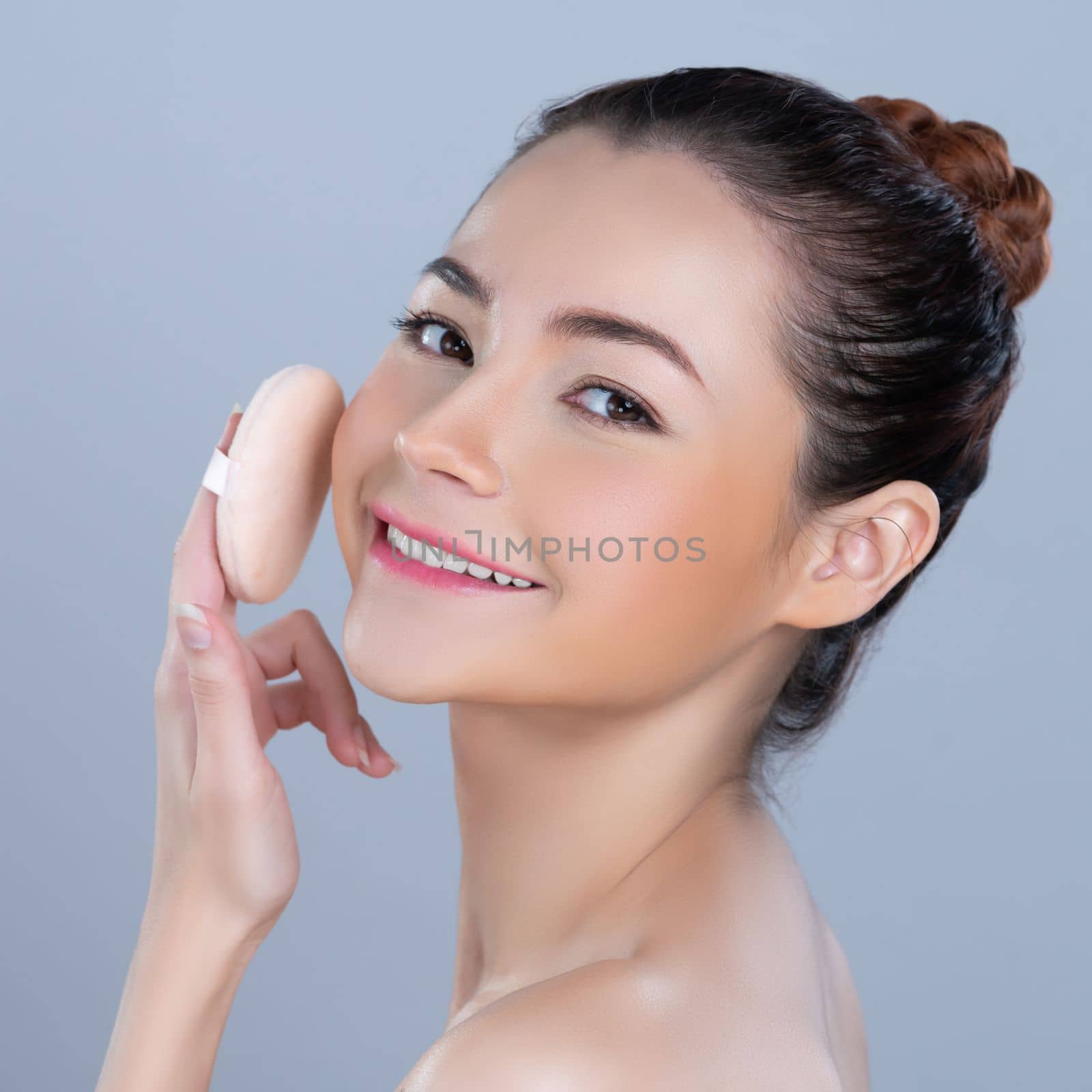Glamorous beautiful female model applying powder puff for facial makeup concept. by biancoblue