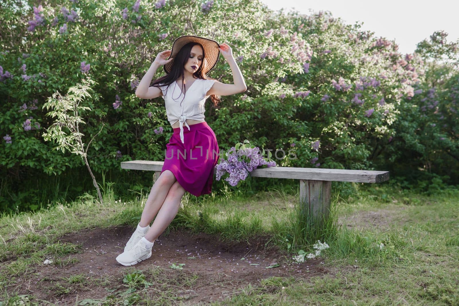 A fashionable girl with dark hair, a spring portrait in lilac tones in summer. Bright professional makeup