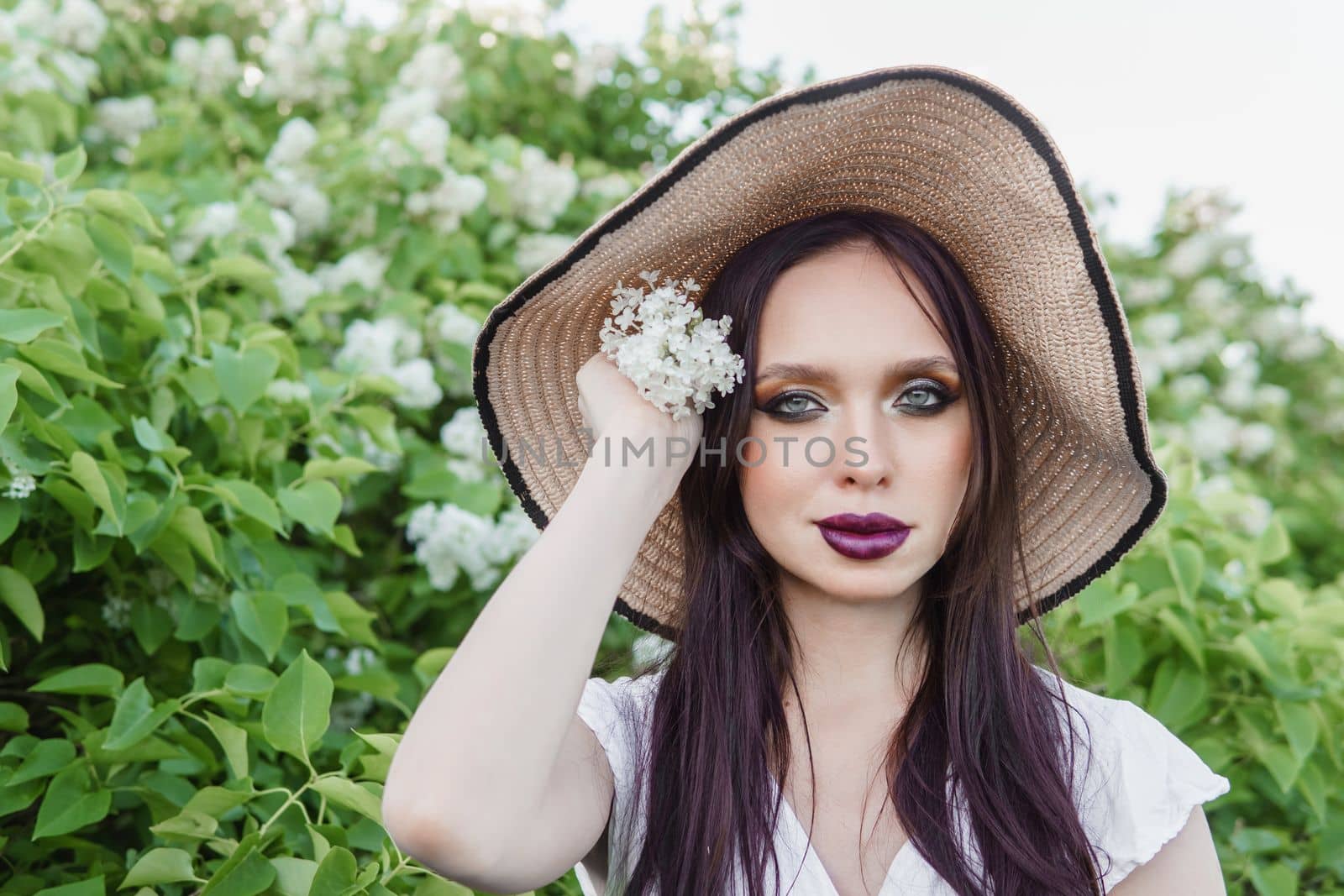 A fashionable girl with dark hair, a spring portrait in lilac tones in summer. Bright professional makeup