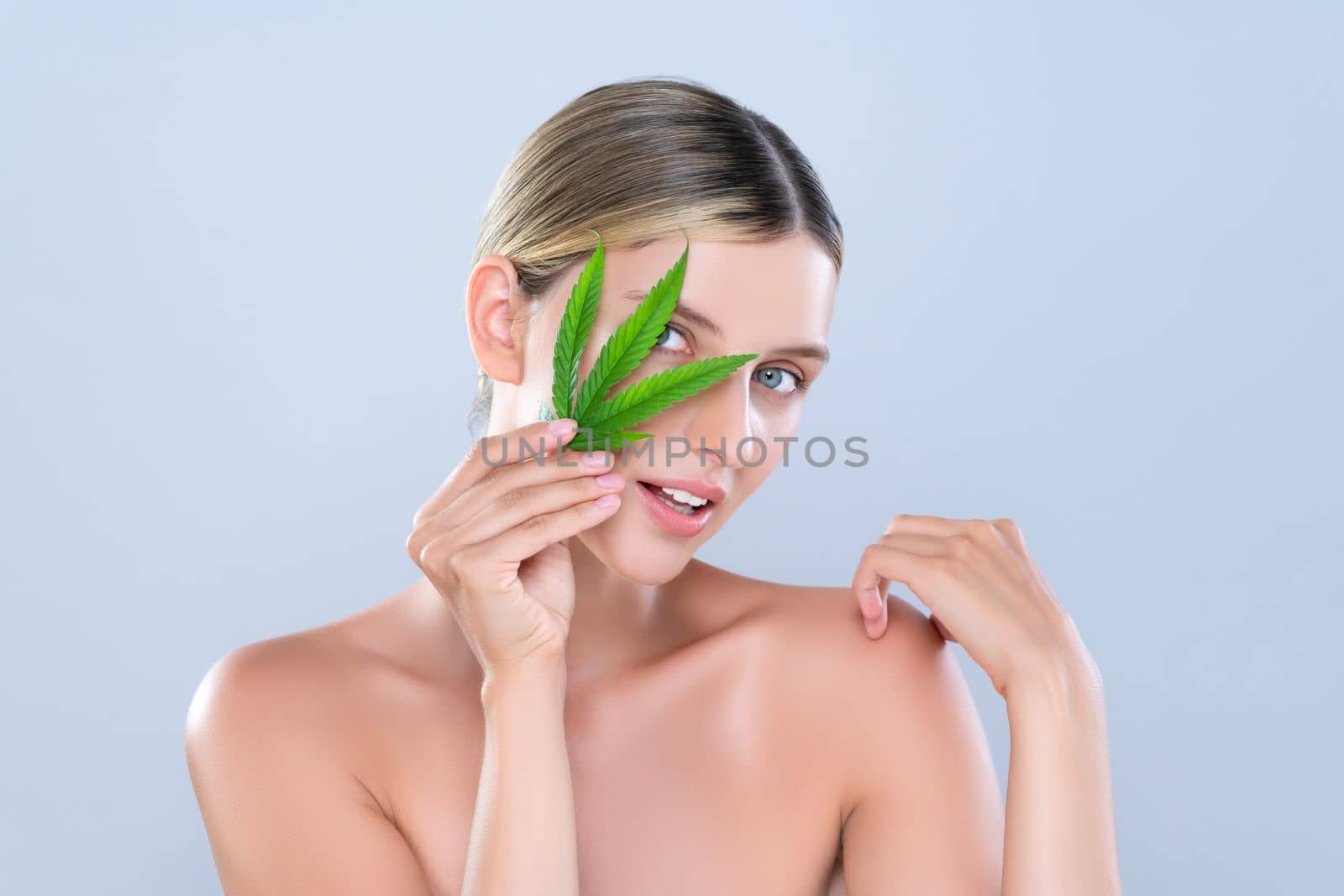 Alluring beautiful woman model portrait holding green leaf as concept for cannabis skincare cosmetic product for skin freshness treatment in isolated background.