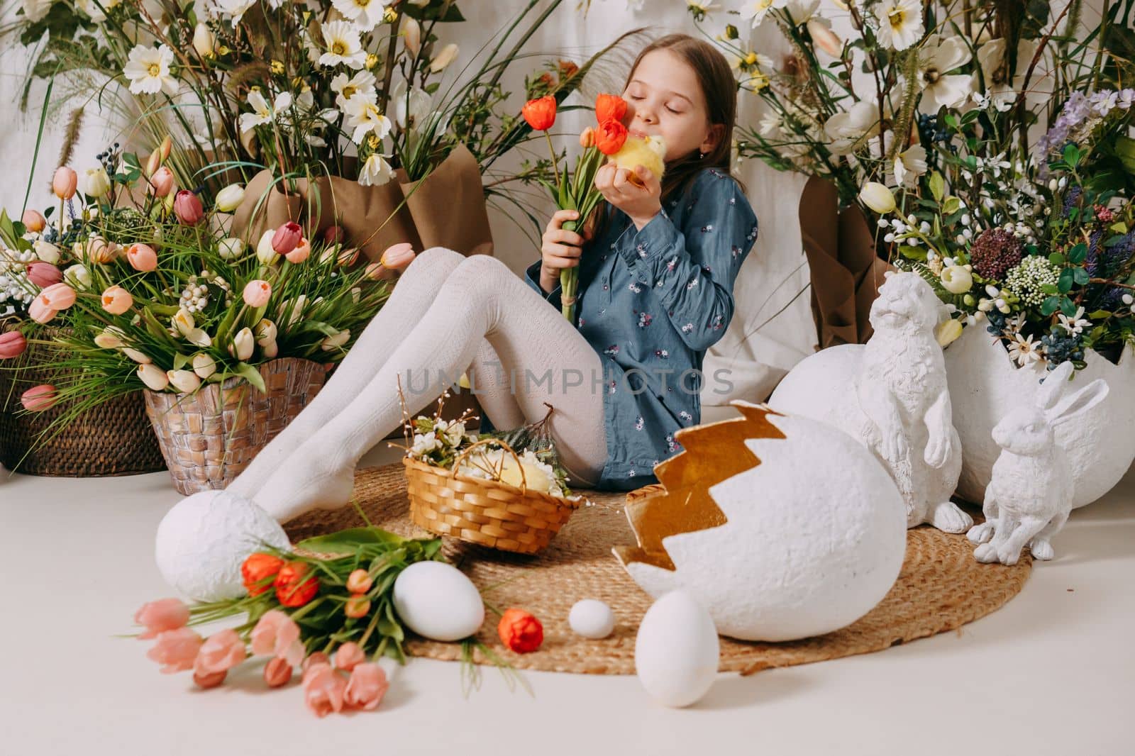 Two girls in a beautiful Easter photo zone with flowers, eggs, chickens and Easter bunnies. Happy Easter holiday