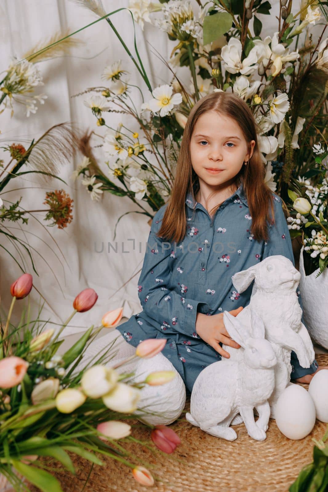 Two girls in a beautiful Easter photo zone with flowers, eggs, chickens and Easter bunnies. Happy Easter holiday