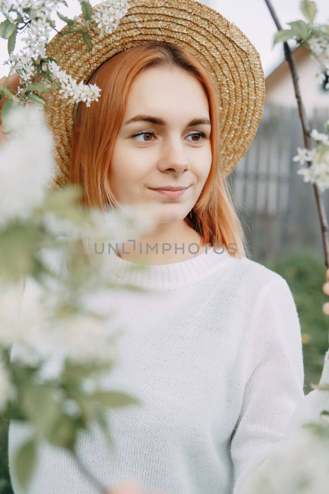 Portrait of a woman in a straw hat in a cherry blossom. Free outdoor recreation, spring blooming garden