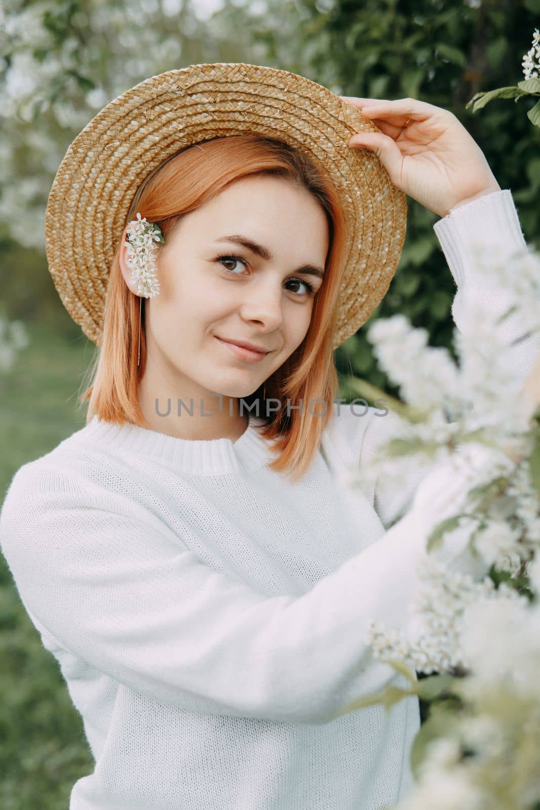 Portrait of a woman in a straw hat in a cherry blossom. Free outdoor recreation, spring blooming garden