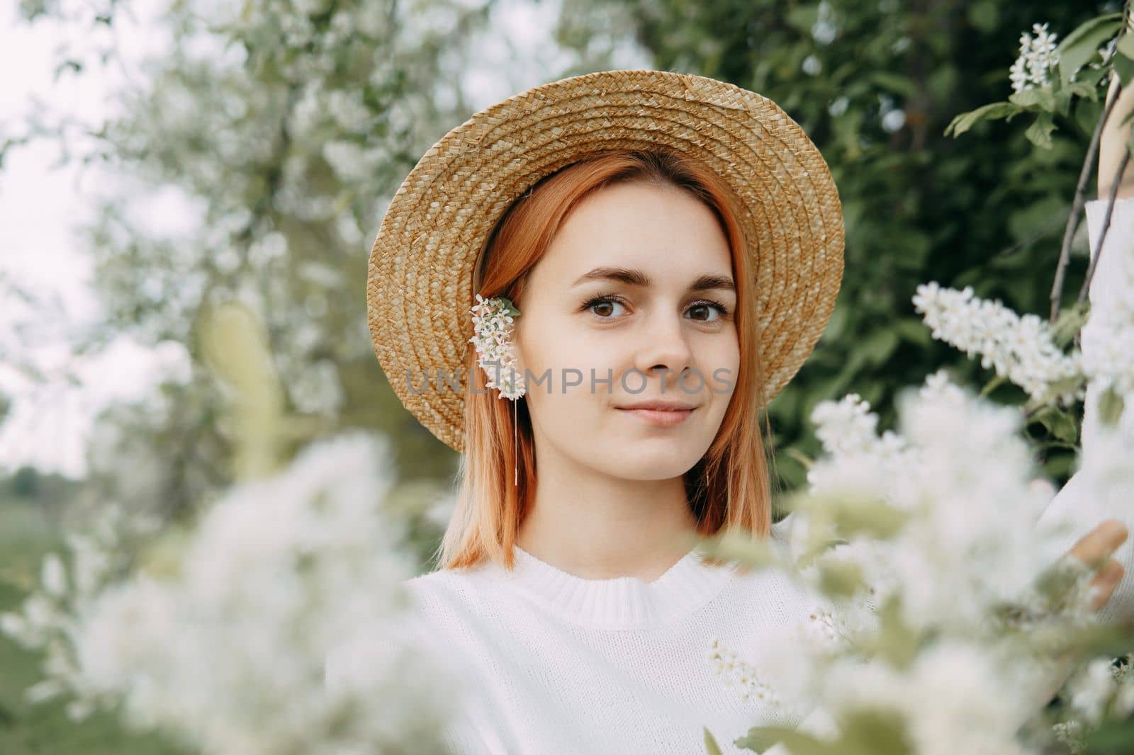 Portrait of a woman in a straw hat in a cherry blossom. Free outdoor recreation, spring blooming garden