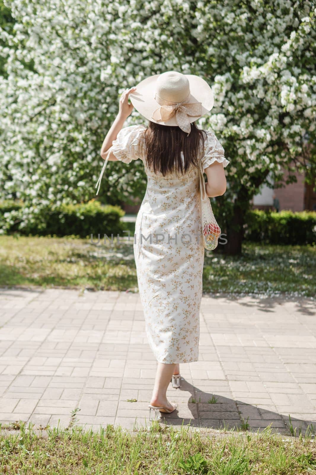 An attractive long-haired woman walks in the spring in the park of blooming apple trees. Spring portrait of a woman