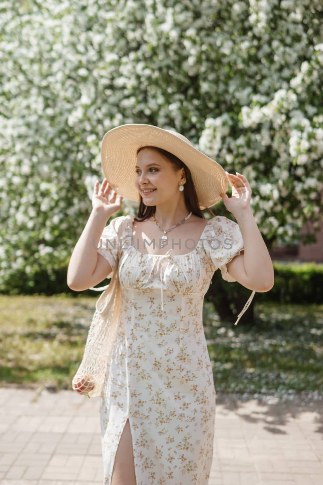 An attractive long-haired woman walks in the spring in the park of blooming apple trees. Spring portrait of a woman