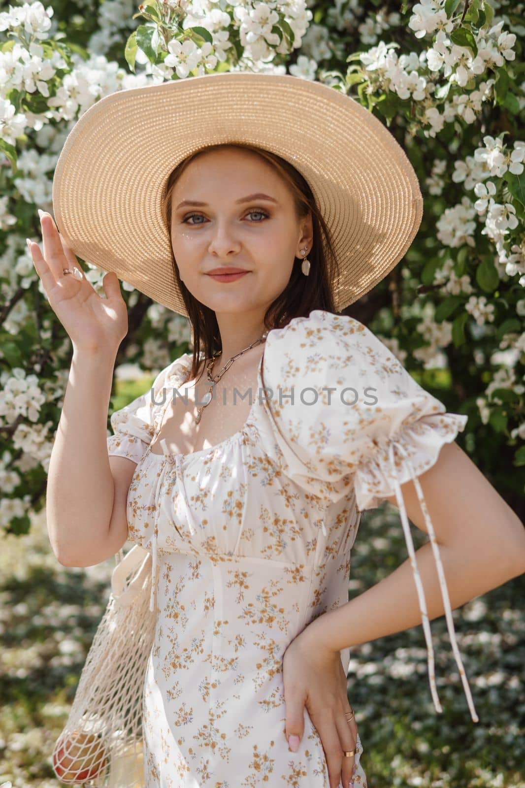 An attractive long-haired woman walks in the spring in the park of blooming apple trees. by Annu1tochka