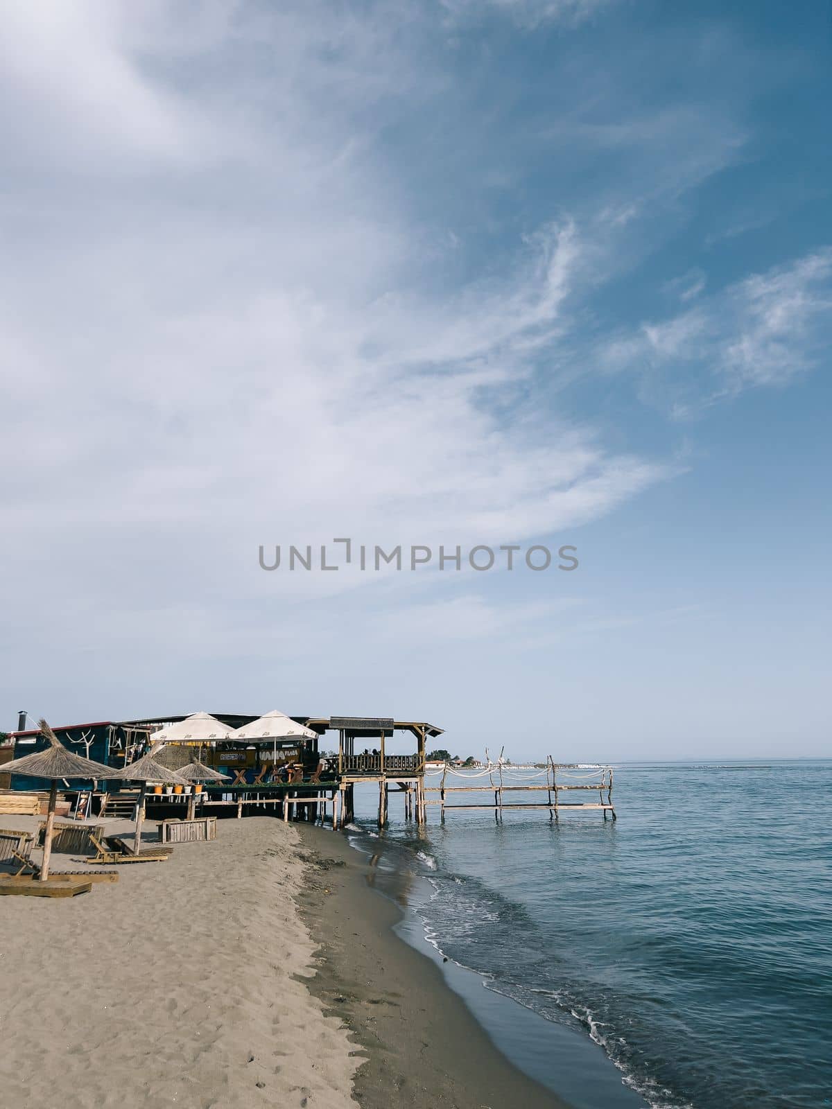 Straw beach umbrellas on a sandy beach by the sea. High quality photo