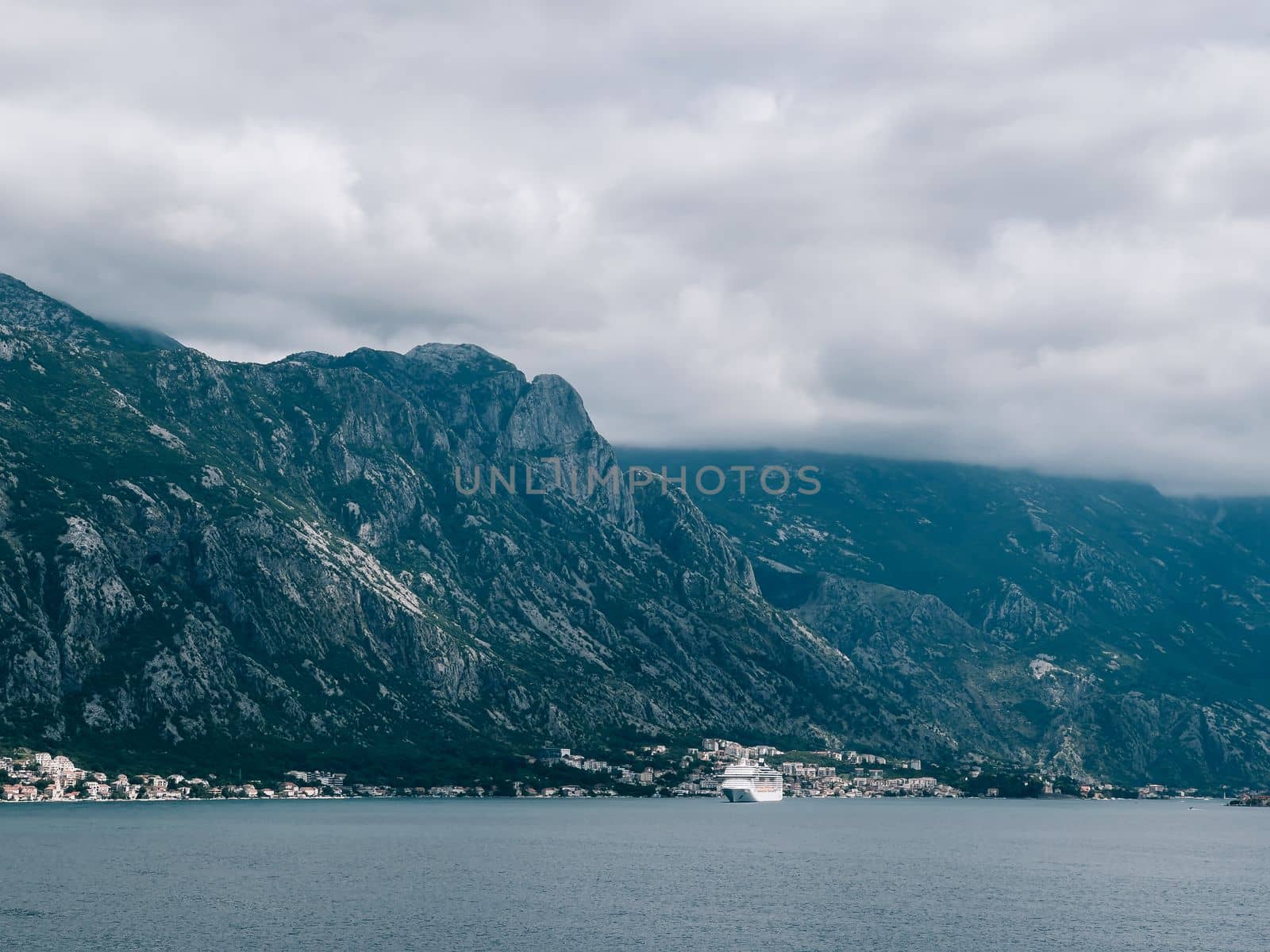 White cruise liner sails along the mountainous coast of the sea. High quality photo
