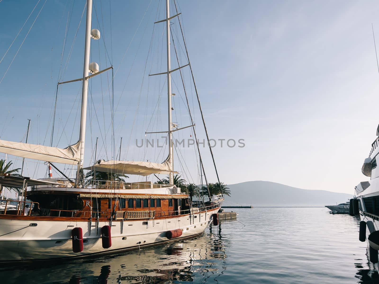 Sailing yacht at the pier with palm trees against the backdrop of mountains. High quality photo