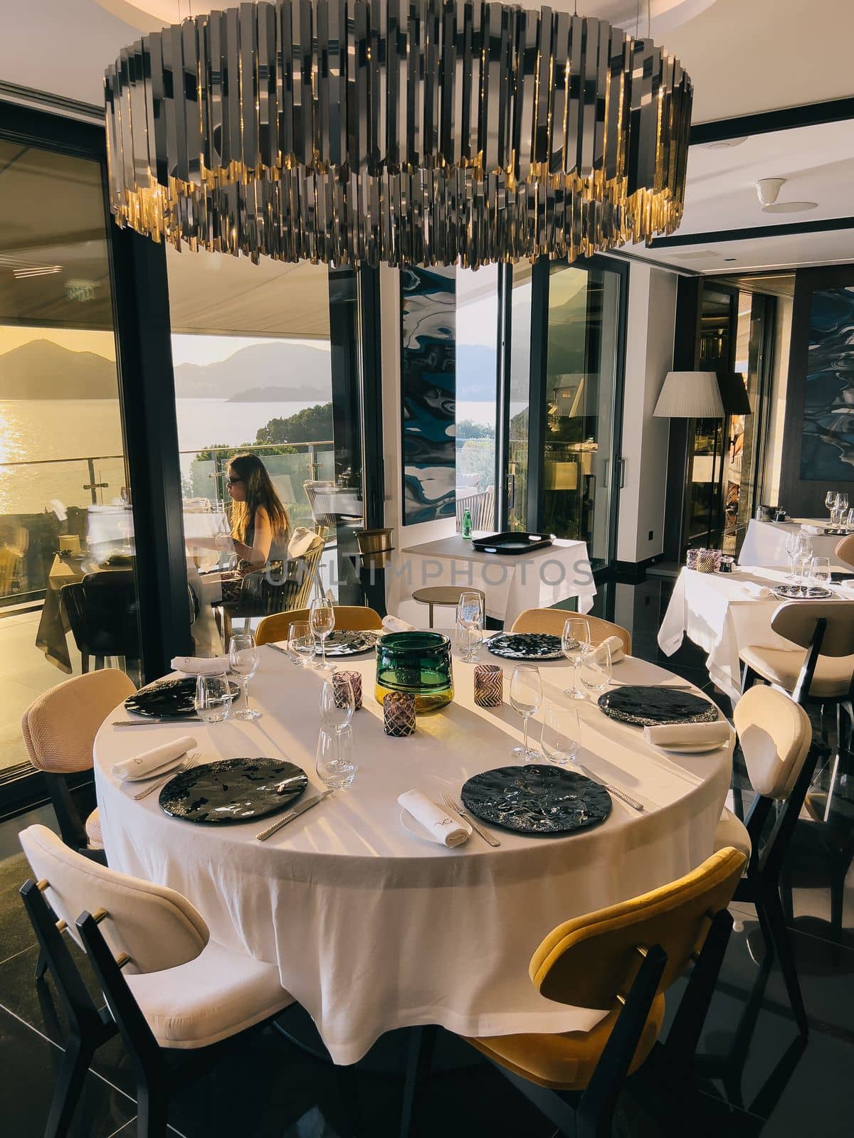 Large chandelier hangs over a set round table in a restaurant. High quality photo