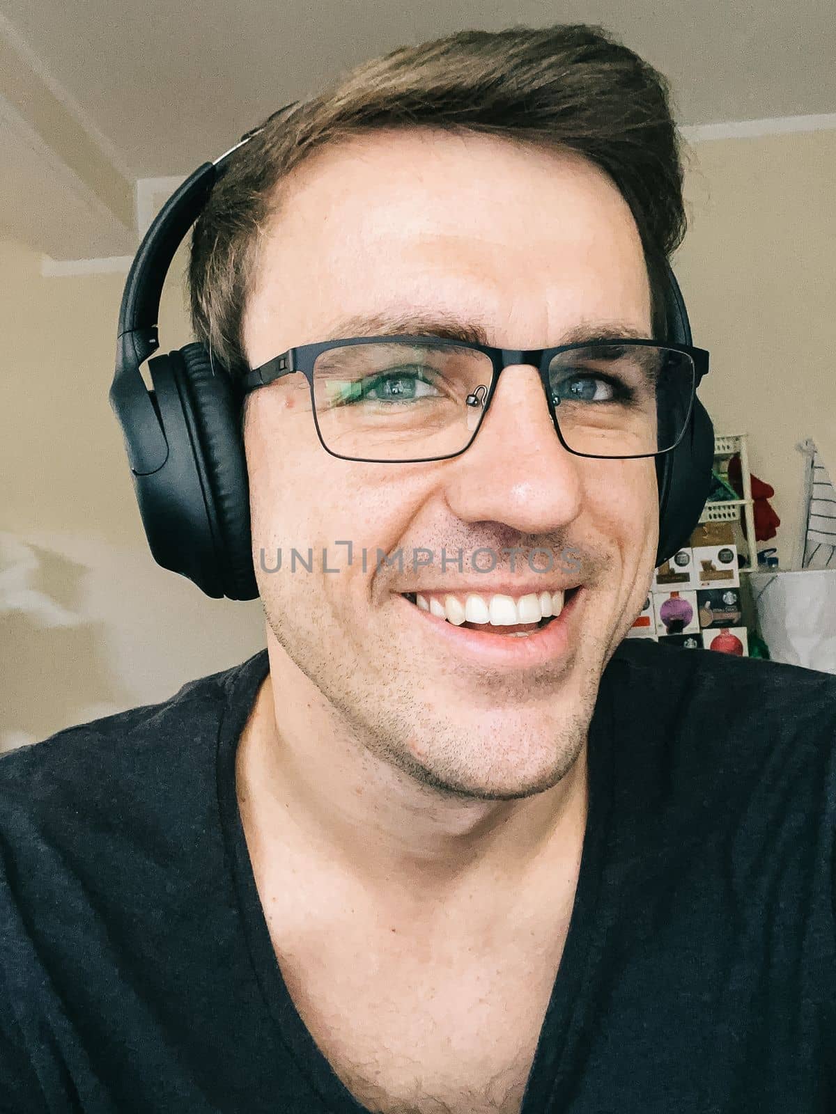 Portrait of a smiling man wearing glasses and wireless headphones. High quality photo