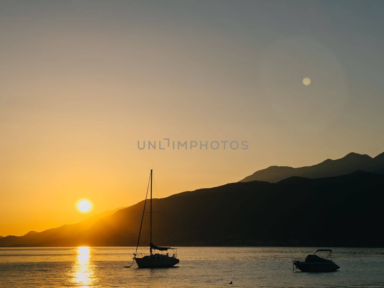 Sailing yacht moored in the sea against the backdrop of mountains at sunset. High quality photo