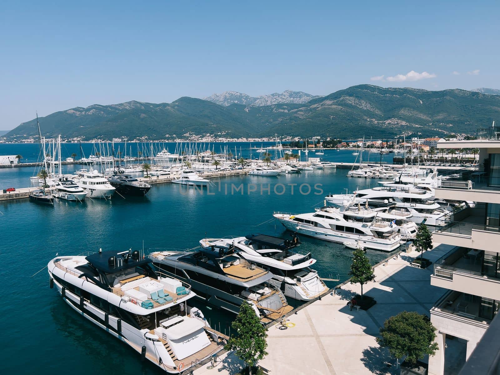 Yachts are moored on the pier near the hotel against the backdrop of the mountains. High quality photo