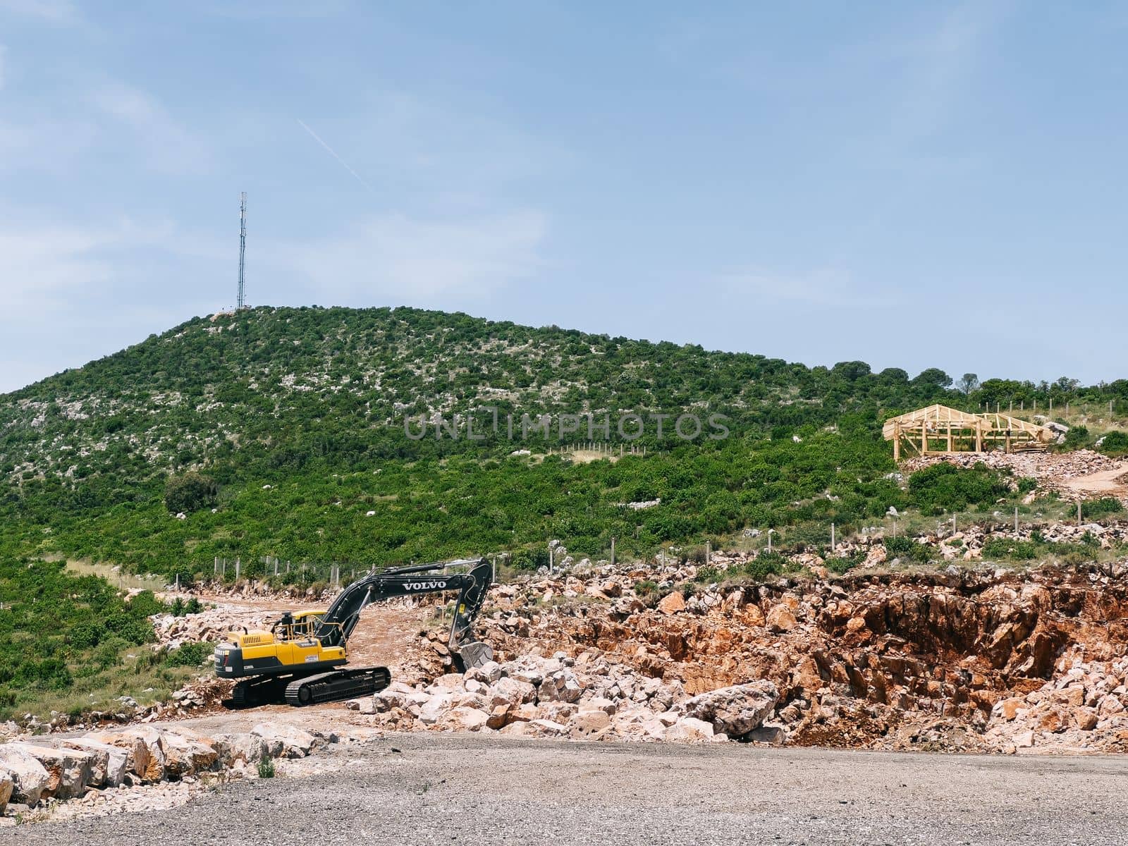 Yellow excavator with a bucket digs stones on a mountainside. High quality photo